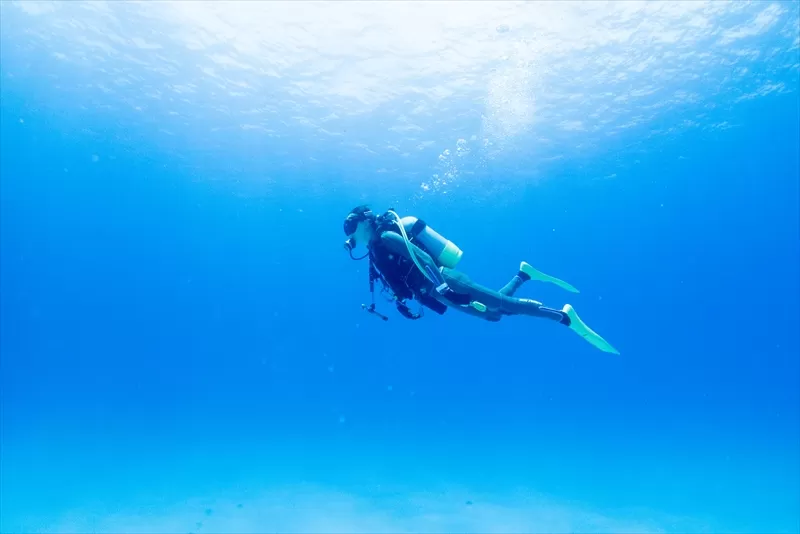 沖縄の波照間島の青い海と青い空、そして白い砂の間で佇む女性ダイバー